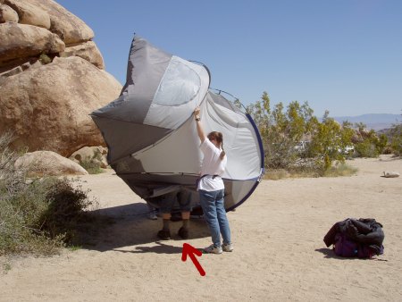 An upraised tent, legs protruding from its door.