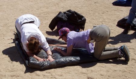 Katie and Sherry kneeling to press the air out of a folded tent.