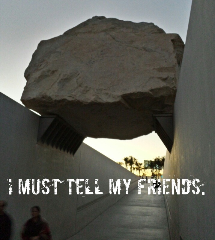Huge boulder suspended by the two walls on either side of a walkway. People can be seen walking along below it. Caption: I must tell my friends.