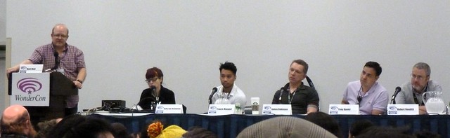 A bunch of comic book writers sitting at a long table with microphones.