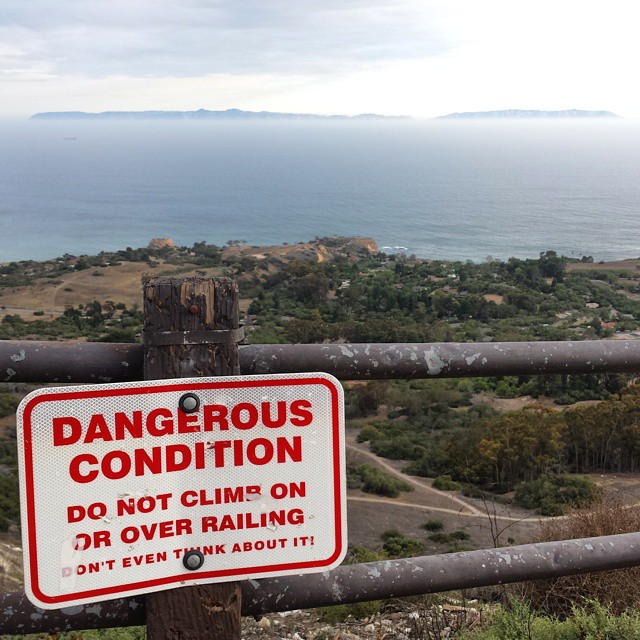 Sign on a fence overlooking a steep drop: DANGEROUS CONDITION - DO NOT CLIMB ON OR OVER RAILING - DON'T EVEN THINK ABOUT IT