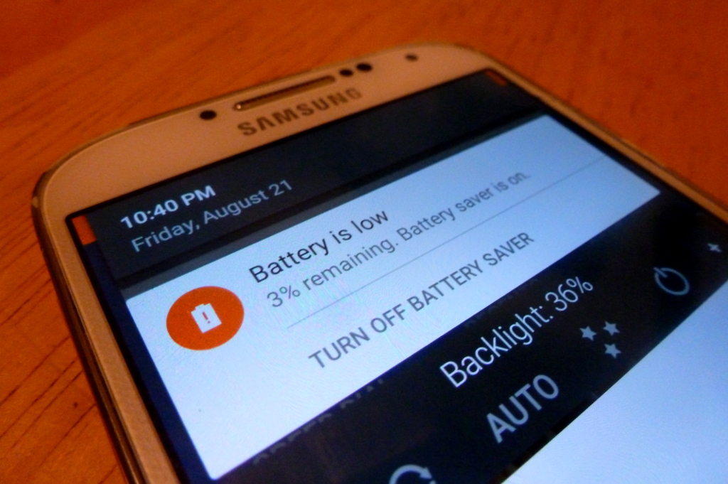 Close-up of the upper part of a Samsung phone. Its screen is displaying a 'Battery is low' warning indicating 3% remaining, and that battery saver mode is on.