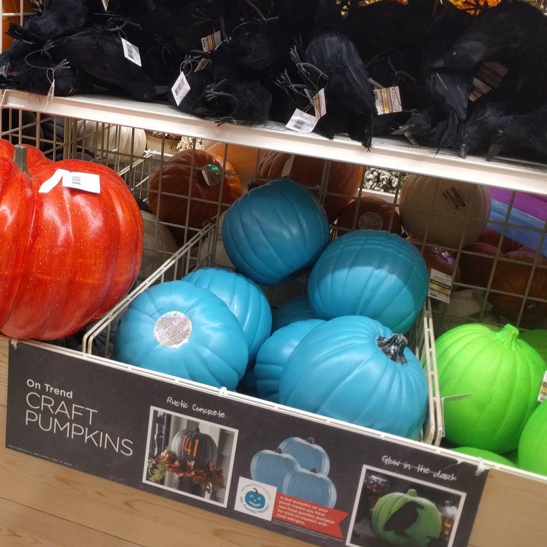 Bins of plastic pumpkins, some colored teal. The Teal Pumpkin Project logo is visible on the bin label.