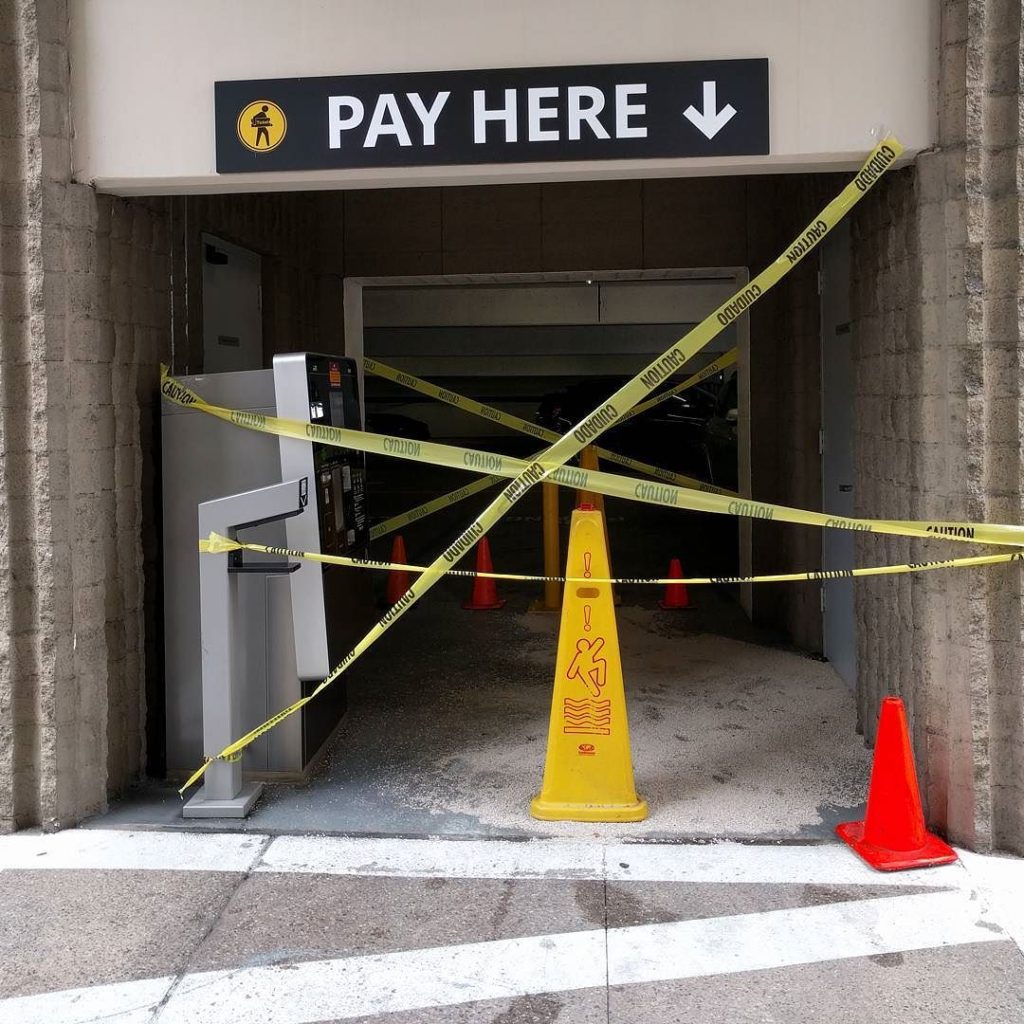 Big sign: Pay Here! Blocked off by caution tape, road cones, and another caution sign.