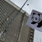 Panda and a crane in front of a building under construction.