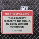Panda hiding behind a NO TRESPASSING sign.