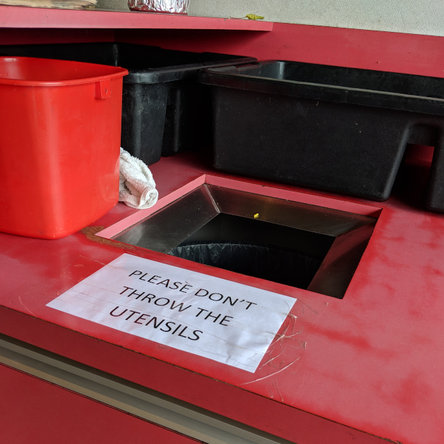 Trash can with sign: Please Don't Throw the Utensils