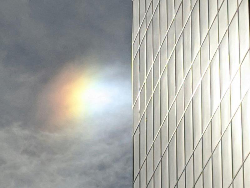 A bright sundog next to a glass-sided building.