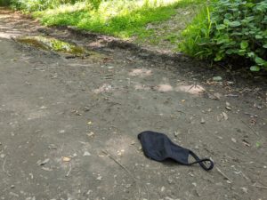 Face mask discarded on a dirt trail.