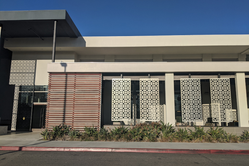 The outside of a building with several tall screens of square patterns in front of it.