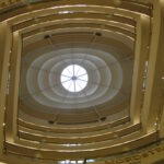 Looking straight up a central gallery with alternating straight and curved railings. The top is a circle surrounded by concentric ovals, resembling a giant eye looking down at the camera. Nordstrom can be read on the lowest visible railing.