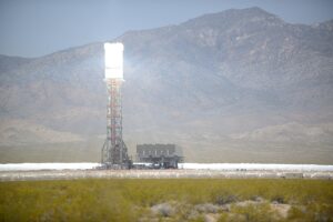 White lines converge through the air from the ground to the top of a narrow tower in the desert. The top of the tower is overexposed white, even though the rest of the image is exposed properly.