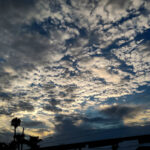 Darkening sky with a bunch of small clouds, lit from behind/below.