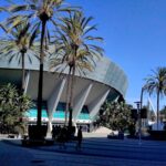 A round, flying-saucer-shaped building on a bright sunny day, flanked with palm trees.